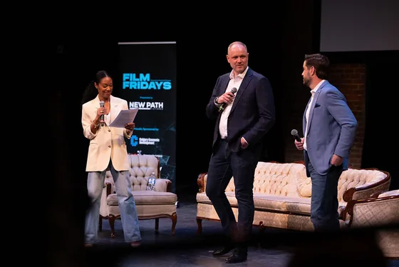 Three participants with microphones introducing the event on stage.
